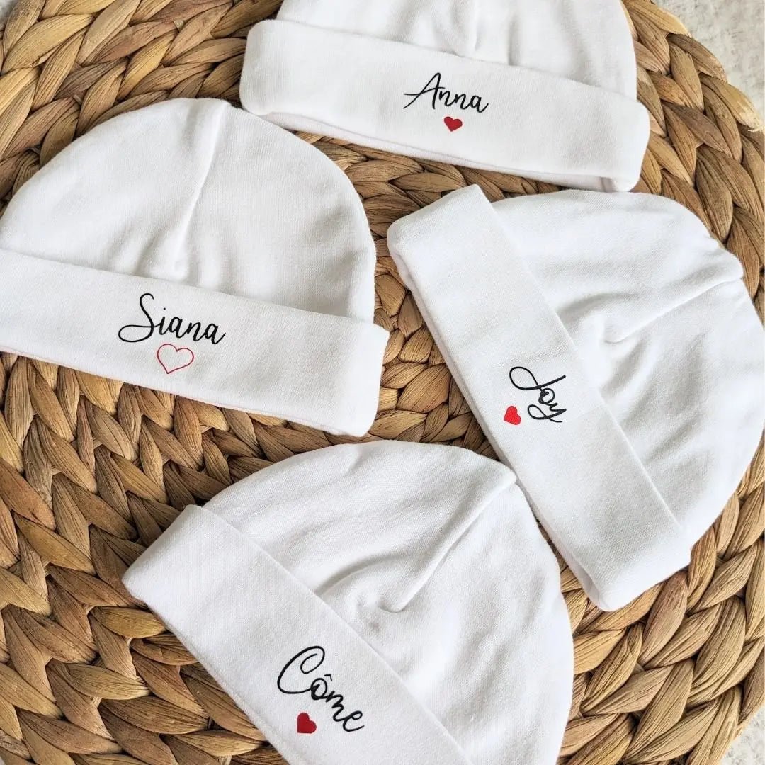 4 bonnets bébés personnalisés, posés sur une table